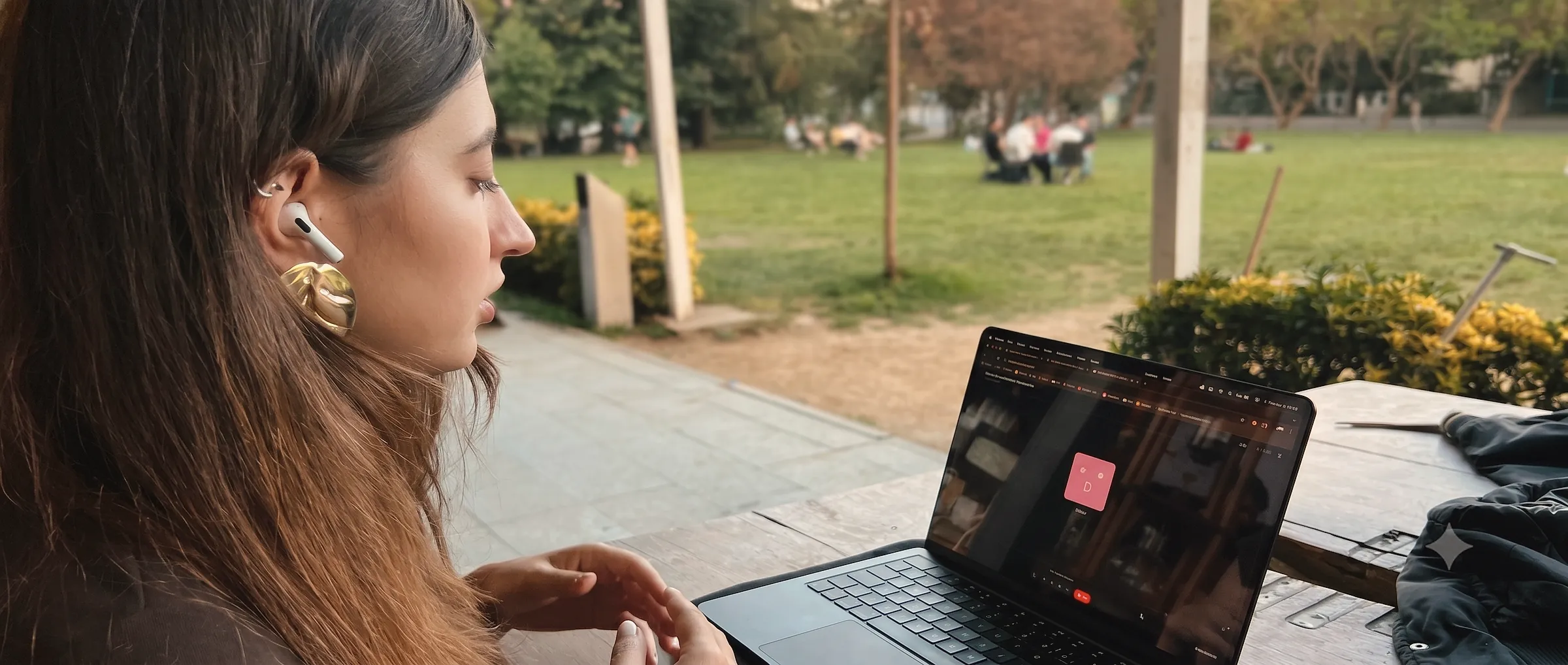 Kablosuz kulaklık takan bir öğrenci, açık havada EVRE'nin canlı sesli AI simülasyonunu çalıştıran bir laptop başında oturuyor.